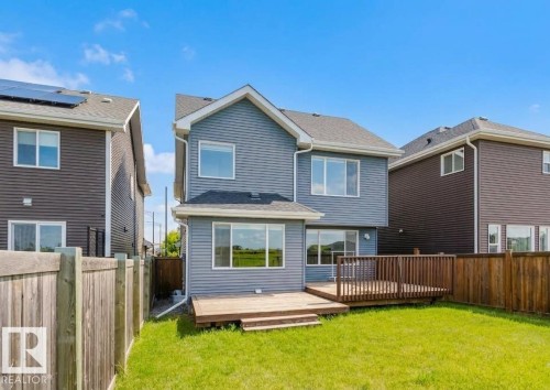 Spacious backyard featuring a large wooden deck and manicured lawn - 16627 18 Avenue, Edmonton, AB 