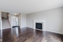 Expansive living area featuring rich wood-finish flooring, a classic white mantel fireplace, and recessed lighting - 16627 18 Avenue, Edmonton, AB 