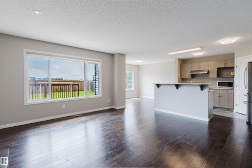 Open-concept living space featuring wood-finish flooring, recessed lighting, and a large picture window - 16627 18 Avenue, Edmonton, AB 