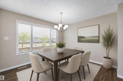 Dining area featuring wood-finish flooring, a large window with blinds, and neutral wall tones - 