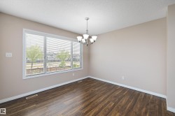 Room featuring wood-finish flooring, a multi-pane window with horizontal blinds, a ceiling-mounted chandelier, and light-toned wall paint - 
