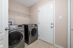 Dedicated laundry room featuring light beige wall paint, tiled flooring, and a built-in wire shelf with hanging rod - 