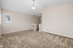 Spacious room featuring vaulted ceilings, neutral-toned walls, and plush carpet flooring - 