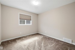 Neutral-toned wall paint with white trim, brown patterned carpet, and a window featuring a cellular shade - 