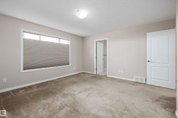 Carpeted room featuring neutral wall tones, a large window with cellular blinds, a semi-flush ceiling light fixture, and white trim - 
