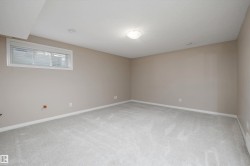 Spacious room featuring light gray carpet, neutral wall paint, white trim, and a horizontal window with blinds - 
