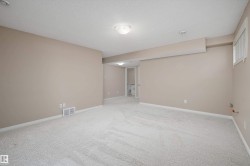 Spacious room featuring neutral-toned walls, light-colored carpeting, white baseboards, and a semi-flush ceiling light fixture - 