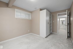 Neutral-toned room featuring light-colored carpeting and a built-in white storage unit with shelving and cabinet doors - 