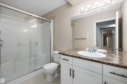 Bathroom featuring a white vanity with dark countertop, an undermount sink, and a large wall mirror - 