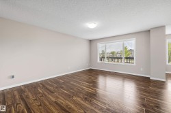 Spacious room featuring wood-finish flooring, a large window with horizontal blinds, neutral wall paint, white trim, and a ceiling light fixture - 