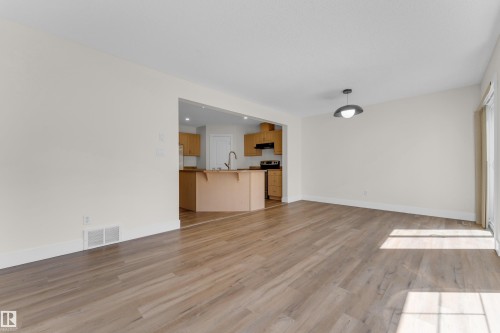 Open concept living space featuring wood-finish flooring and a contemporary pendant light fixture - 64 14208 36 Street, Edmonton, AB 