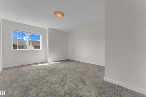 Bright interior space featuring a multi-pane window, neutral wall paint, white trim, textured ceiling, and a flush-mount ceiling light - 64 14208 36 Street, Edmonton, AB 