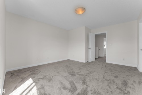 Spacious room featuring neutral carpeting, light-toned wall paint, and white trim - 64 14208 36 Street, Edmonton, AB 