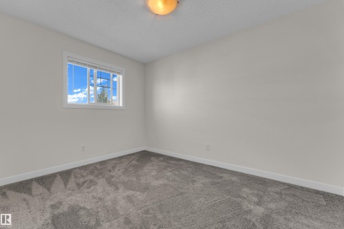 Room featuring light gray walls, gray patterned carpet flooring, and a white-framed window - 64 14208 36 Street, Edmonton, AB 