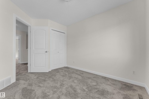 Spacious room featuring neutral carpeting, white trim, and a white interior door - 64 14208 36 Street, Edmonton, AB 