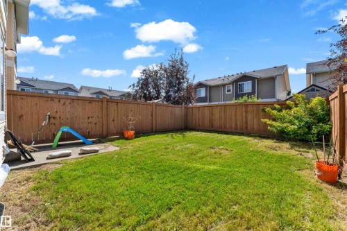 Fenced backyard featuring a manicured lawn and a concrete patio area - 64 14208 36 Street, Edmonton, AB 