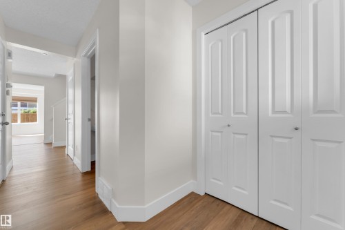 Hallway featuring wood-finish flooring, white baseboards, and bright white walls - 64 14208 36 Street, Edmonton, AB 