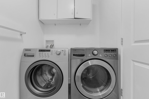 Laundry area featuring dual front-load appliances, upper cabinetry, and a wall-mounted hanging rod - 64 14208 36 Street, Edmonton, AB 