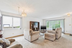 Spacious living area featuring light-colored carpeting and white walls - 