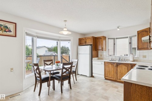 Bright kitchen featuring wood cabinetry, white appliances, light-toned countertops, and a bay window - 9315 168 Avenue Nw, Edmonton, AB 