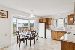 Bright kitchen featuring wood cabinetry, white appliances, light-toned countertops, and a bay window - 