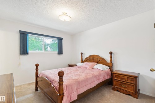 Carpeted room with a textured ceiling and a single window featuring horizontal blinds - 9315 168 Avenue Nw, Edmonton, AB 