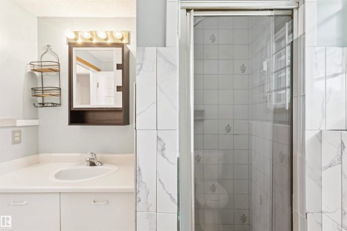 Bathroom featuring a vanity with integrated sink, chrome faucet, and a wall-mounted medicine cabinet with integrated lighting - 9315 168 Avenue Nw, Edmonton, AB 
