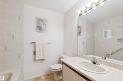 Bathroom featuring a spacious vanity with integrated sink, a large wall-mounted mirror, and tile-surround bathtub - 