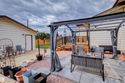 Backyard patio featuring a pergola with retractable privacy screens, a raised wooden deck with black railings, and a concrete patio area - 