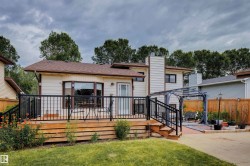 Rear exterior with a multi-level wood-finish deck featuring black metal railings - 