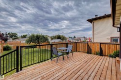 Spacious outdoor wood-finish deck with black metal railings - 