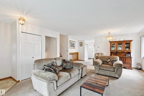 Spacious living area featuring carpeted flooring, white walls, and a ceiling-mounted light fixture - 9315 168 Avenue Nw, Edmonton, AB 