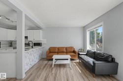 Open concept living area featuring wood-finish flooring, a large window, and light gray walls - 