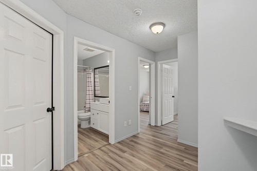 Hallway featuring wood-finish flooring, light grey painted walls, and white trim - 5 14603 Miller Boulevard, Edmonton, AB 