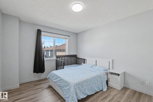 Bedroom featuring wood-finish flooring, a contemporary ceiling light fixture, and a large window - 5 14603 Miller Boulevard, Edmonton, AB 