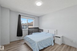 Bedroom featuring wood-finish flooring, a contemporary ceiling light fixture, and a large window - 
