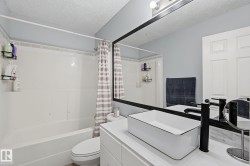 Bathroom featuring a white vanity with an integrated vessel sink, black faucet, and a large wall-mounted mirror with black trim - 