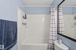Bathroom featuring a shower-tub combination, tiled surround, and a ceiling with textured finish - 