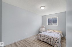Bedroom featuring light gray walls, wood-finish flooring, and a white-framed window - 