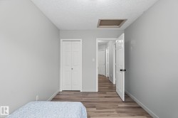 Bedroom featuring wood-finish flooring, light grey painted walls, and a white bi-fold closet door - 