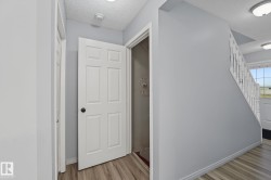 Foyer featuring wood-finish flooring, light gray wall paint, a classic white six-panel door, and a white staircase with spindle railing - 