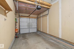 Attached garage featuring a concrete floor, a paneled garage door, and a garage door opener system - 