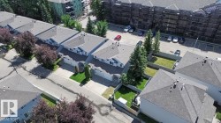Row of townhomes featuring light-colored siding, attached garages, and gray shingle roofing - 