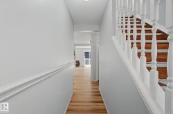 Entryway featuring wood-finish flooring, white trim, and a staircase with white balusters and wood treads - 