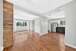 Open-concept interior featuring wood-finish flooring, recessed lighting, and a prominent wood-panel accent wall - 