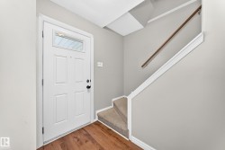 Entryway featuring wood-finish flooring and a white paneled door with an upper glass insert - 