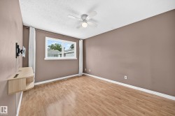Room featuring wood-finish flooring, a white trim baseboard, and a ceiling fan with integrated lighting - 