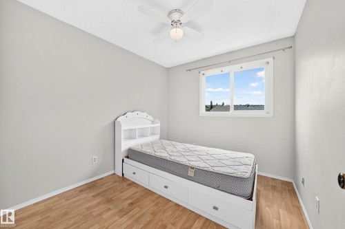 Bright room featuring light wood-finish flooring, a ceiling fan with light fixture, and a large window - 32 Mcleod Place, Edmonton, AB 