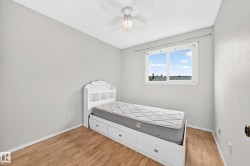 Bright room featuring light wood-finish flooring, a ceiling fan with light fixture, and a large window - 