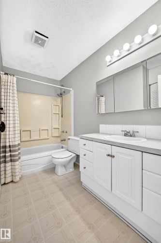 Bathroom featuring a single vanity with white cabinetry, a built-in sink, and a tiled backsplash - 32 Mcleod Place, Edmonton, AB 